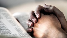 Praying hands over Bible